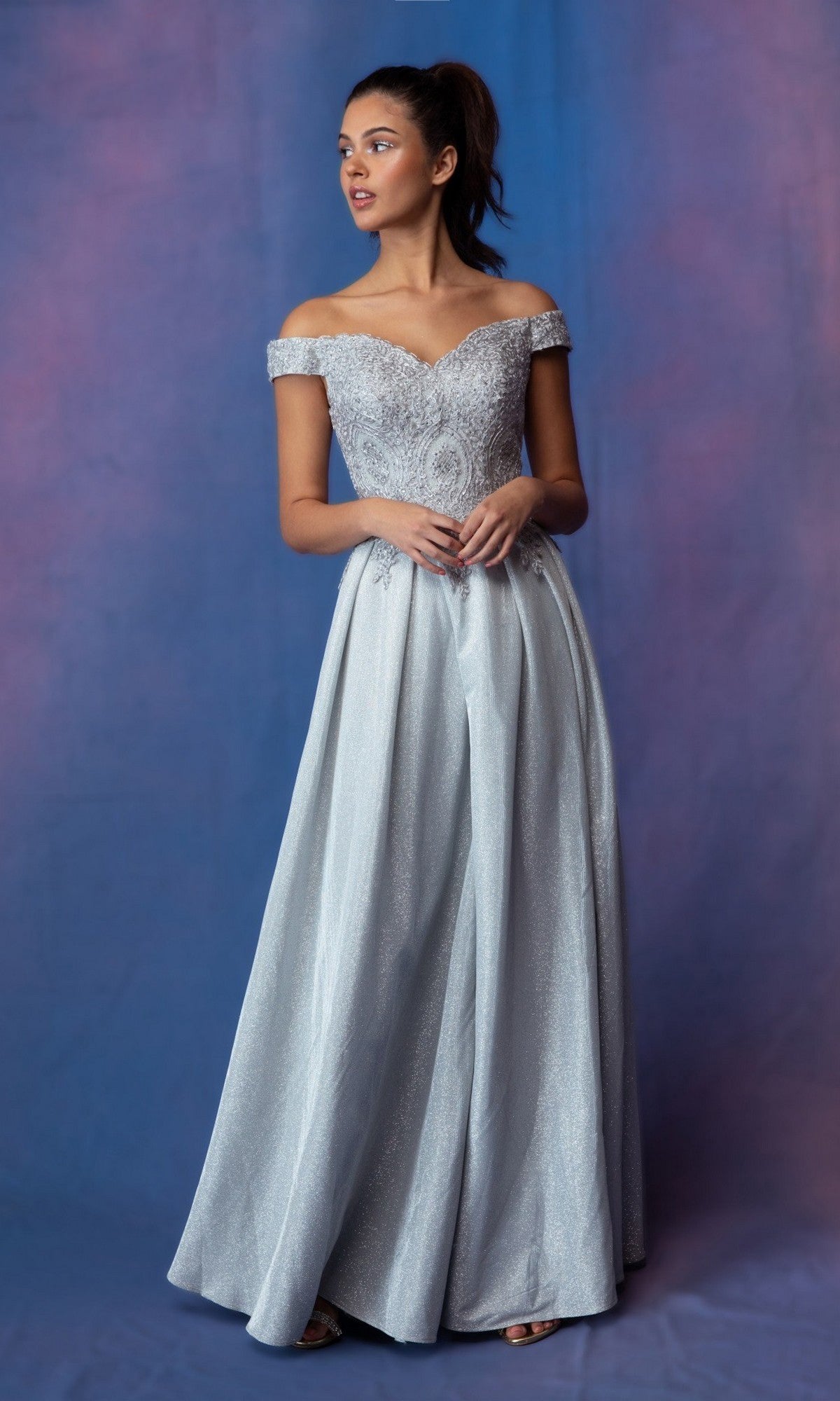 A woman models the Eureka 9806 long prom dress in silver, featuring an off-the-shoulder fitted bodice and glitter A-line skirt, set against a blue and purple gradient background.